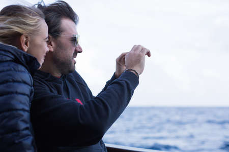 Side view of father and daughter taking photo against of sea