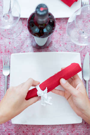 Woman holding napkin with ceramic napkin ring in form of angel. Romantic served table on background. Unrecognizableの写真素材