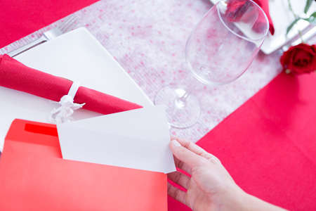 Woman getting paper sheet from envelope. Decorated table on background. Unrecognizableの写真素材