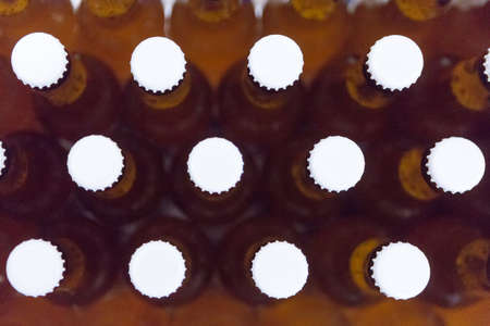 Close-up of full beer bottles with white lids. From above. Useful as a backgroundの写真素材