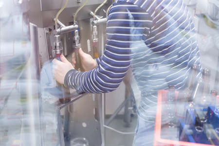 Unrecognizable man behind glass using hardware for craft beerの写真素材