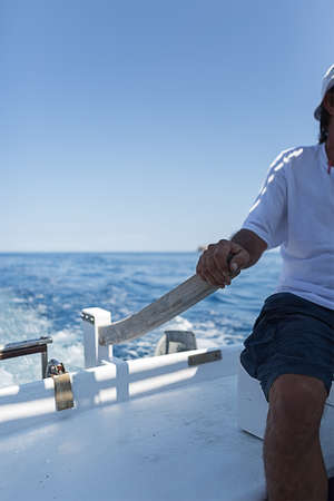 Unrecognizable sailor ruddering boat  against of blue sky. Copy spaceの写真素材