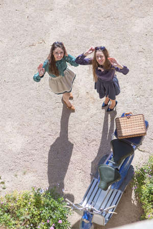 View from above on two elegant women near blue vintage motorbike with suitcasesの写真素材