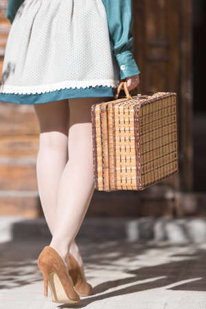 Unrecognizable woman walking with wattled suitcase while wearing high heels and skirtの写真素材