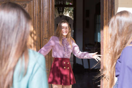 Young woman smiling while  standing at door entrance, guests are coming.の写真素材