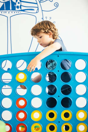 Portrait of curly-haired cute boy playing educational game in kindergartenの写真素材