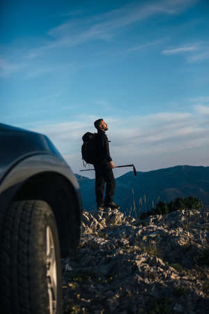 Side view of bearded mountaineer with backpack looking away against of mountains.Copy space