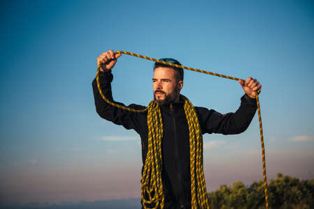 Portrait of bearded adult man with yellow rope looking away.Blue sky on backgroundの写真素材