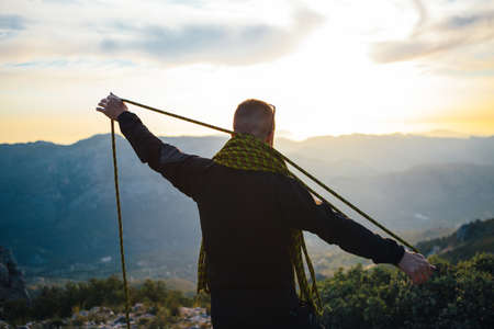 Back view of traveler with yellow rope against of sunset in mountainsの写真素材