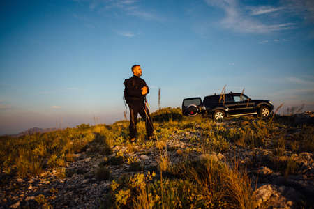 Pensive backpacker looking away against of car