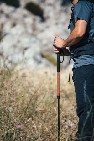 Close-up of unrecognizable traveler with climbing stick in sunlightの写真素材