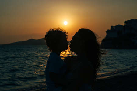 Silhouette of family kiss against of sunset at sea. Backlitの写真素材