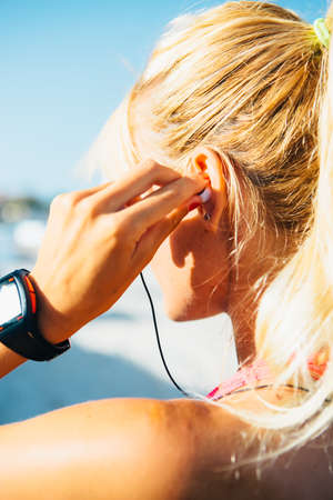 CLose-up of unrecognizable runner putting earphones in sunlightの写真素材