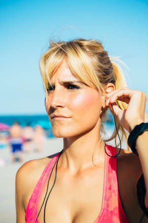 Close-up of blonde sportswoman listening to music on beachの写真素材