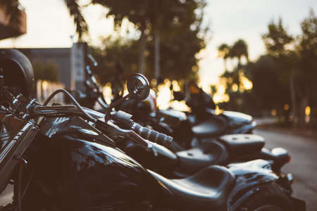 Line of parked motorcycles in evening street. Bokeh trees backgroundの写真素材