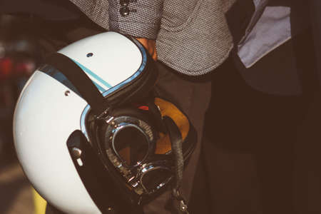 Close-up of unrecognizable man holding white vintage helmet with glasses in sunlightの写真素材