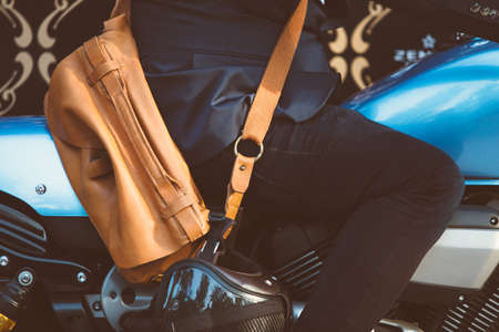 Side view of unrecognizable man with bag and helmet sitting on blue bikeの写真素材