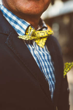 Close-up of unrecognizable man wearing yellow bowtie with screws and nailsの写真素材