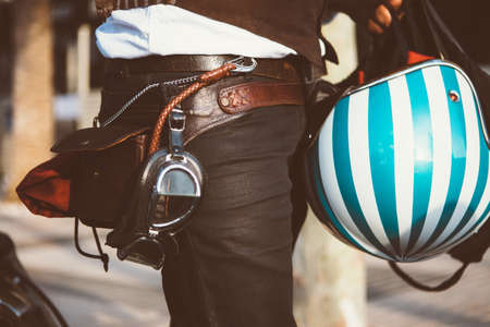 Close-up of unrecognizable person holding bright stripy bike helmet with vintage glasses in sunlightの写真素材