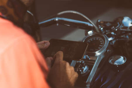 Close-up of unrecognizable man browsing smartphone while sitting on bikeの写真素材