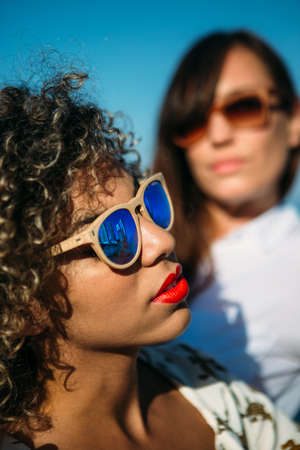 Portrait of adorable mixed race woman in sunglasess with curly hair and bright red lipsの写真素材