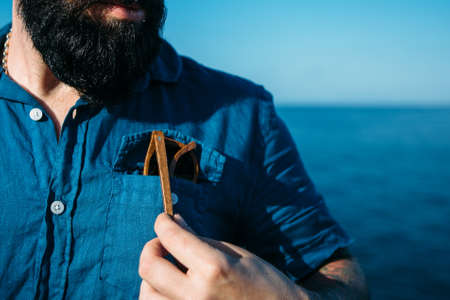 Portrait of unrecognizable stylish bearded man in blue shirt takes sunglasses from pocket.の写真素材