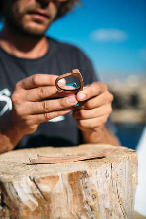 Close up of unrecognizable male master treats handmade wooden rim glasses