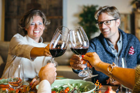 People cheering at celebration table with wine glasses and smiles on their faces. Close up view of...