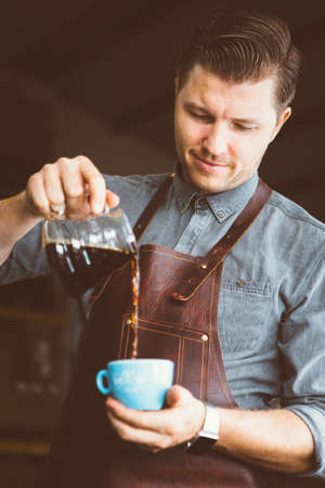 Portrait of smiling barista pouring fresh black coffee in cupの写真素材