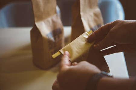 close-up of unrecognizable worker packing roasted coffee in bagsの写真素材