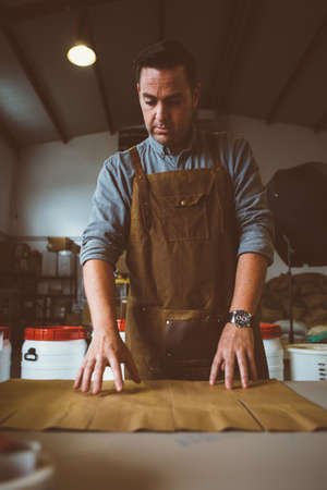 Portrait of adult worker looking down at coffee bag in line on table