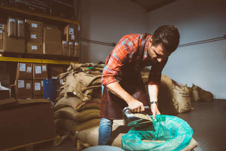 professional coffee roaster filling bag with scoop of coffee beans
