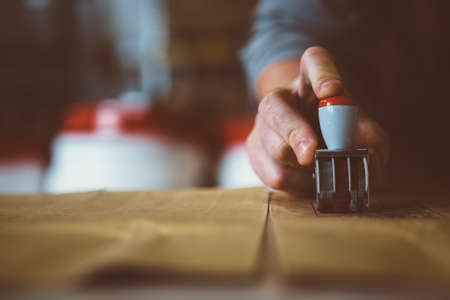 Close-up of unrecognizable worker putting stamp on paper packageの写真素材