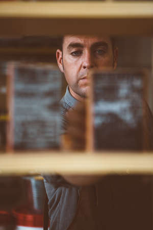 Portrait of adult worker arranging unfocused shelf with object in close-upの写真素材