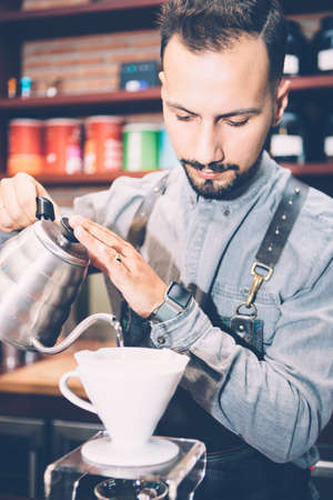 Portrait of professional coffeemaker pouring hot water from kettle in chemexの写真素材