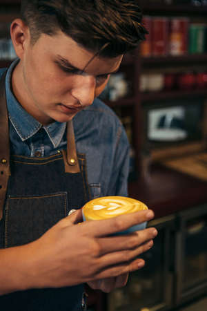 Portrait of professional barista holding cup of latte art