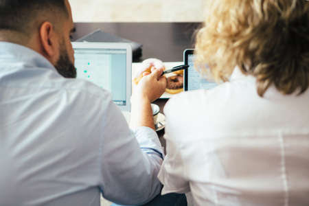 Man pointing at screen with pen.Unrecognizable woman