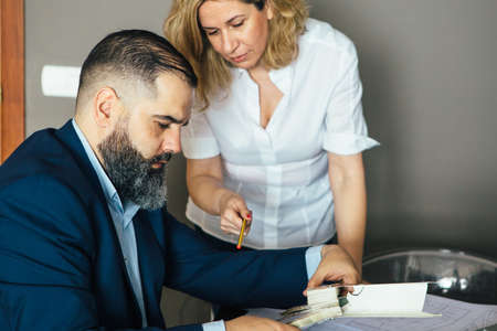 Blonde adult designer pointing at color palette in man's hands