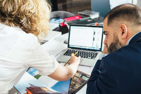 Back view of unrecognizable female designer showing illustrated book with designs to man