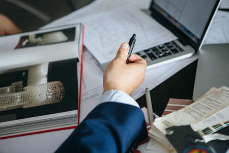 unrecognizable man with pen at table with open book with chandelier photosの写真素材