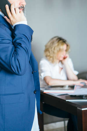 Unrecognizable businessman talking over cell against of unfocused woman at table