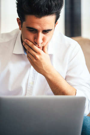 Portrait of thoughtful young businessman looking down at laptop