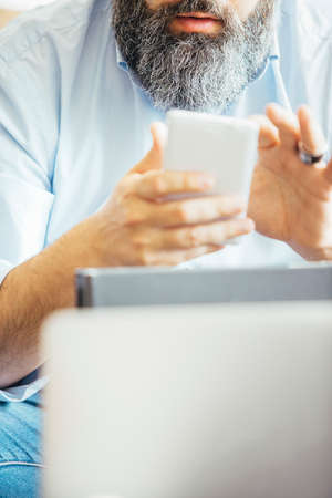 Unrecognizable businessman typing on cell in daylight