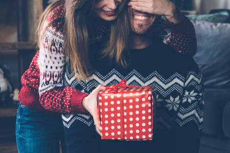 Young woman covering man's eyes with hand and springing surprise. の写真素材