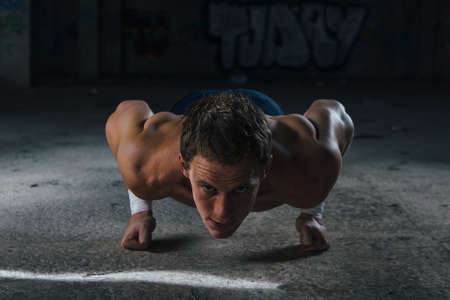 Man pushing up on his fists and looking at camera. Horizontal indoors shot