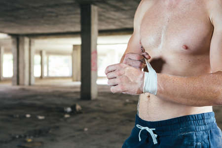 Front view of man with naked torso touching elastic bandage in hand.の写真素材