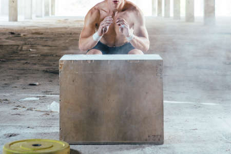 Front view of faceless muscular man doing box jumps in abandoned building.の写真素材