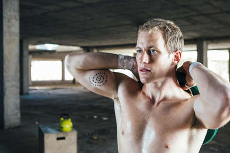 Front view of young strong man holding weight behind back. Horizontal indoor shotの写真素材