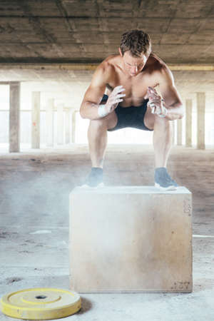 Front view of muscular man doing box jumps. Vertical indoor shotの写真素材
