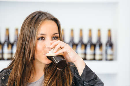 portrait of beautiful brunette drinking glass of dark craft beerの写真素材